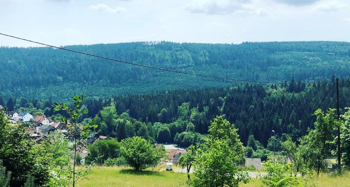 Blick auf ein Dorf umgeben von grünen Wäldern und Hügeln unter einem bewölkten Himmel., © Nördlicher Schwarzwald Blick auf ein Dorf umgeben von grünen Wäldern und Hügeln unter einem bewölkten Himmel., © Nördlicher Schwarzwald