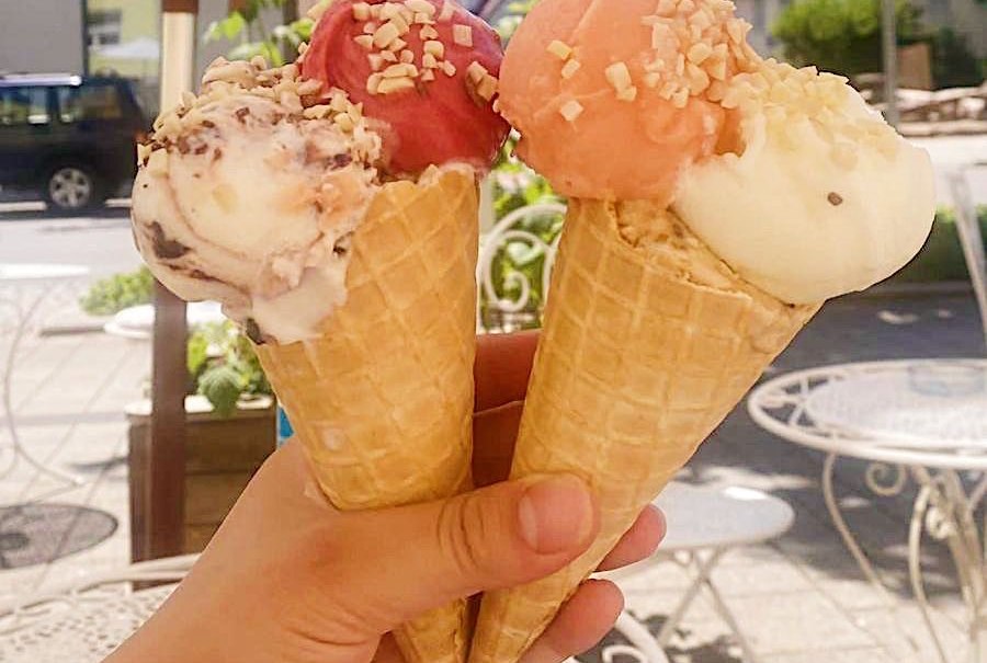 Drei Eiswaffeln mit verschiedenen Eissorten und Nüssen, gehalten von einer Hand unter einem Sonnenschirm im Freien., © E. Dogan Drei Eiswaffeln mit verschiedenen Eissorten und Nüssen, gehalten von einer Hand unter einem Sonnenschirm im Freien., © E. Dogan