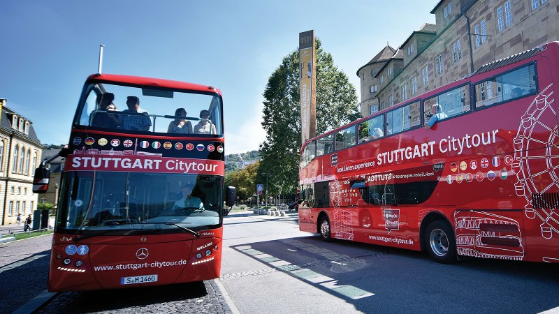Zwei rote Doppeldeckerbusse der Stuttgart Citytour stehen vor dem Landesmuseum Württemberg. Menschen sitzen auf dem offenen Oberdeck., © Stuttgart-Marketing GmbH, Pierre Polak