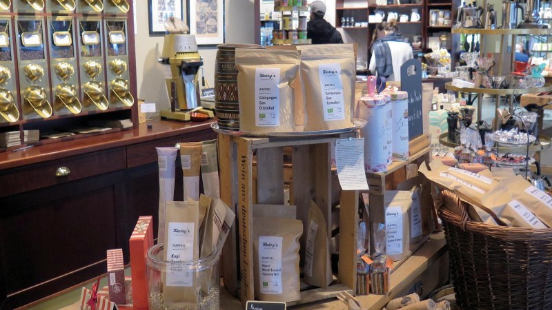 Verkaufsraum einer Kaffeerösterei mit goldenen Kaffeespendern, Kaffeetüten und verschiedenen Produkten auf Holztischen und Regalen., © Stuttgart-Marketing GmbH, Lara Seeger