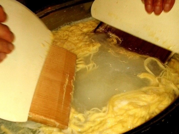 Zwei H&auml;nde schaben Sp&auml;tzleteig mit Brettern in kochendes Wasser. Traditionelle Zubereitung von Sp&auml;tzle in einem Kochkurs., &copy; Kultweine-Kochwelten-Kunst&uuml;cke - Kochschule Sonja Lenz