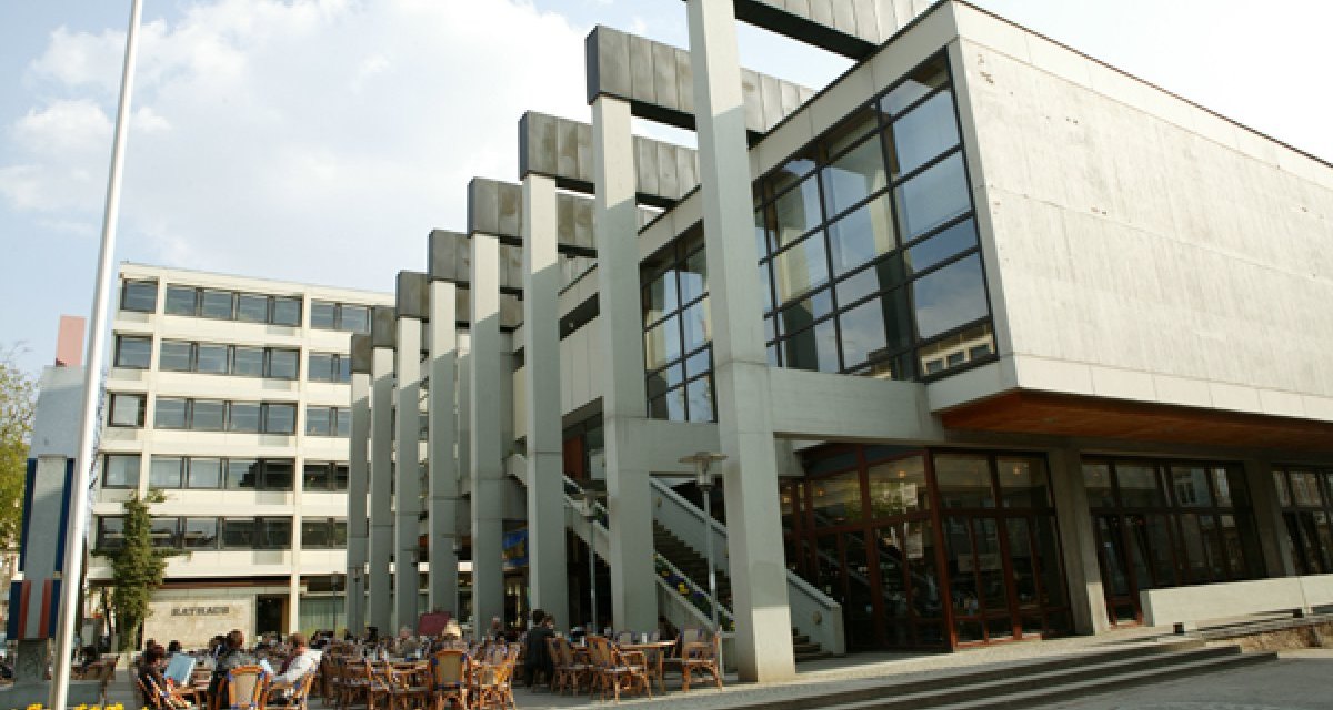 Das Reutlinger Rathaus mit moderner Architektur, Glasfassade und Außenterrasse. Menschen sitzen an Tischen im Freien. Himmel ist leicht bewölkt., © Sphäre Verlag Das Reutlinger Rathaus mit moderner Architektur, Glasfassade und Außenterrasse. Menschen sitzen an Tischen im Freien. Himmel ist leicht bewölkt., © Sphäre Verlag