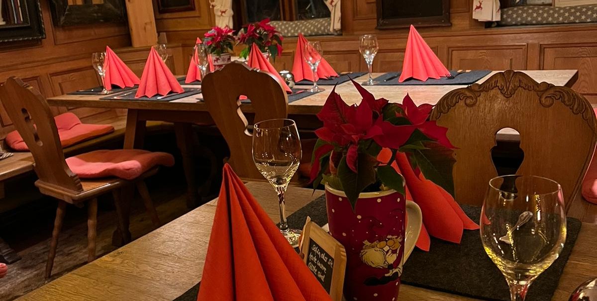 Gem&uuml;tliche Weinstube mit festlich gedecktem Tisch, roten Servietten und stimmungsvoller Beleuchtung. Weihnachtsdekoration sorgt f&uuml;r ein einladendes Ambiente., &copy; cWeinstube