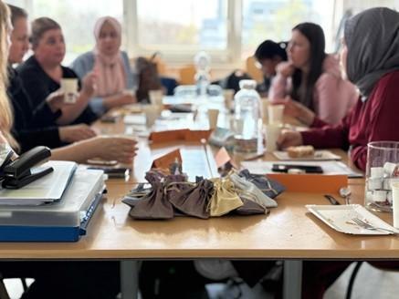 Frauen und M&auml;dchen sitzen an einem Tisch und diskutieren in einem Workshop. Auf dem Tisch liegen Notizb&uuml;cher und Stifte., &copy; Stadtbibliothek Ludwigsburg
