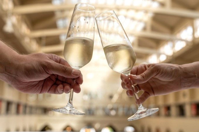 Zwei Personen sto&szlig;en mit Sektgl&auml;sern in einer lichtdurchfluteten Halle an, vermutlich in der Stuttgarter Markthalle., &copy; Stuttgart Marketing GmbH