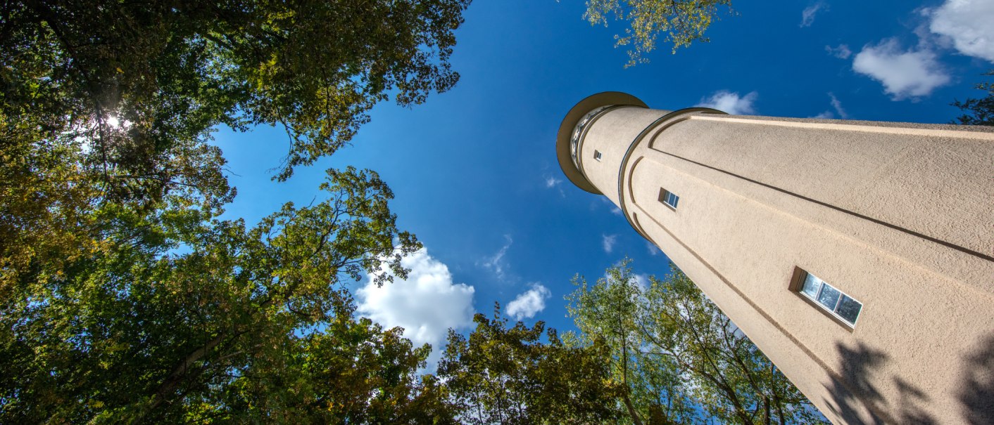 Der Engelbergturm in Leonberg ragt in den blauen Himmel, umgeben von gr&uuml;nen B&auml;umen und wei&szlig;en Wolken., &copy; SMG, Achim Mende
