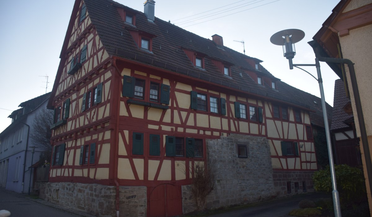 Fachwerkhaus mit roten Balken und grünen Fensterläden in einer schmalen Straße. Eine Straßenlaterne steht rechts im Bild., © Land der 1000 Hügel - Kraichgau-Stromberg Fachwerkhaus mit roten Balken und grünen Fensterläden in einer schmalen Straße. Eine Straßenlaterne steht rechts im Bild., © Land der 1000 Hügel - Kraichgau-Stromberg