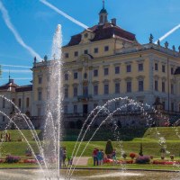 Das Residenzschloss Ludwigsburg mit einem großen Springbrunnen im Vordergrund. Der Himmel ist blau mit Kondensstreifen, umgeben von gepflegten Gärten., © Tourismus & Events Ludwigsburg