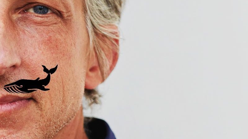 Nahaufnahme eines Mannes mit grauen Haaren und einem Wal-Tattoo auf der Wange, vor einem neutralen Hintergrund., © Backnang Nahaufnahme eines Mannes mit grauen Haaren und einem Wal-Tattoo auf der Wange, vor einem neutralen Hintergrund., © Backnang