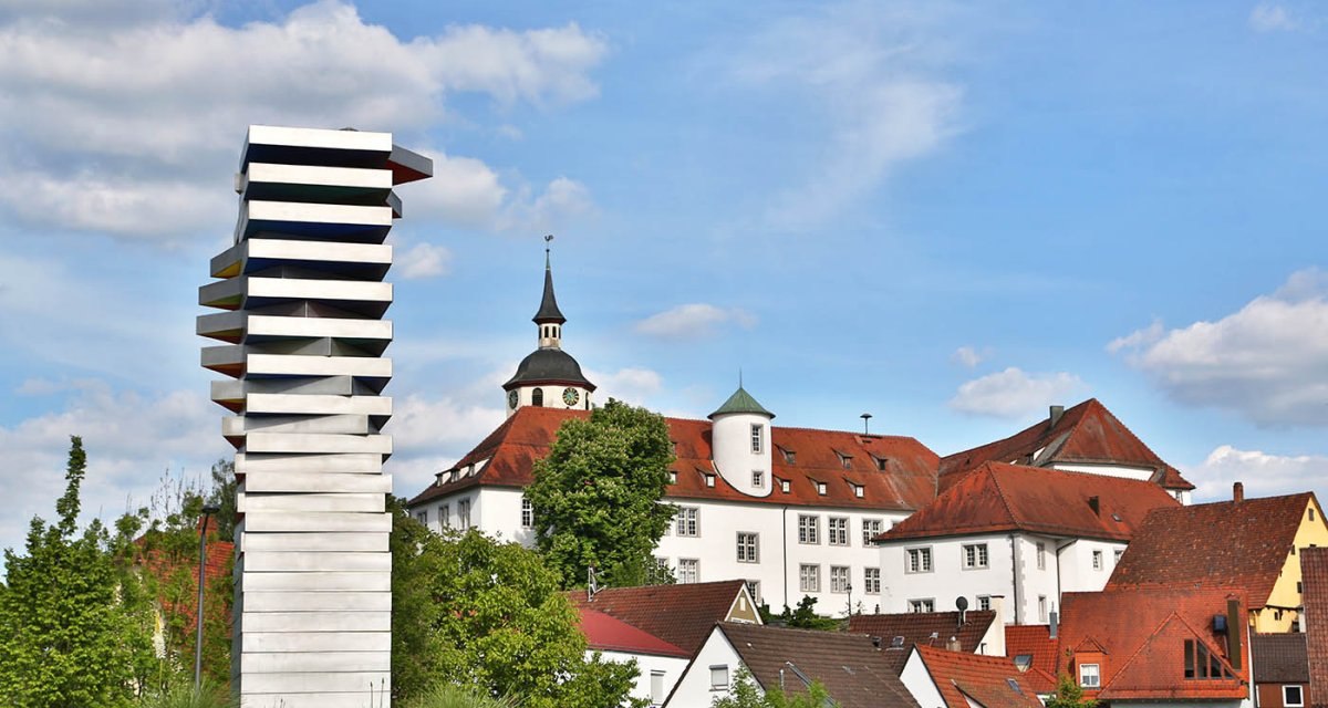Moderne Skulptur vor Schloss Waldenbuch mit rotem Dach und Kirchturm im Hintergrund, umgeben von grünen Bäumen und blauem Himmel., © Region Stuttgart Moderne Skulptur vor Schloss Waldenbuch mit rotem Dach und Kirchturm im Hintergrund, umgeben von grünen Bäumen und blauem Himmel., © Region Stuttgart