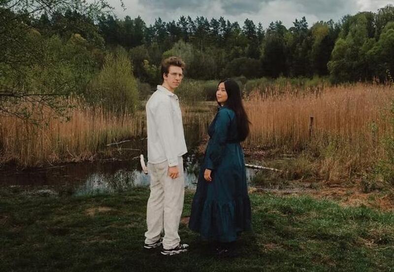 Zwei Personen stehen in eleganter Kleidung vor einem Teich in einer bewaldeten Landschaft. Der Himmel ist bewölkt., © Jazzclub Schwäbisch Hall e.V. Zwei Personen stehen in eleganter Kleidung vor einem Teich in einer bewaldeten Landschaft. Der Himmel ist bewölkt., © Jazzclub Schwäbisch Hall e.V.
