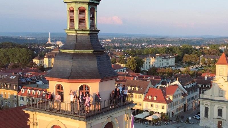 Menschen genie&szlig;en den Ausblick vom Kirchturm auf den Ludwigsburger Marktplatz im warmen Abendlicht. Historische Geb&auml;ude und eine weite Landschaft sind sichtbar., &copy; Copyright: Tourismus & Events Ludwigsburg, Fotograf: ArtusTV