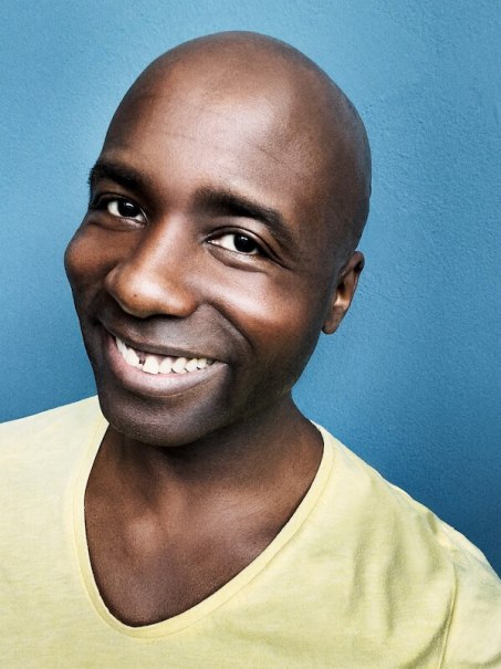 Ein Mann mit Glatze lächelt in die Kamera. Er trägt ein gelbes T-Shirt und steht vor einem blauen Hintergrund., © Veranstaltungsring Metzingen e.V. Ein Mann mit Glatze lächelt in die Kamera. Er trägt ein gelbes T-Shirt und steht vor einem blauen Hintergrund., © Veranstaltungsring Metzingen e.V.