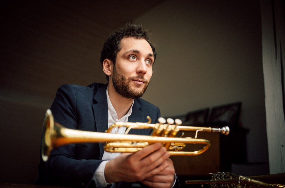 Ein Mann im Anzug hält eine Trompete und schaut nachdenklich zur Seite. Der Hintergrund ist unscharf., © copyright_LukasDiller Ein Mann im Anzug hält eine Trompete und schaut nachdenklich zur Seite. Der Hintergrund ist unscharf., © copyright_LukasDiller