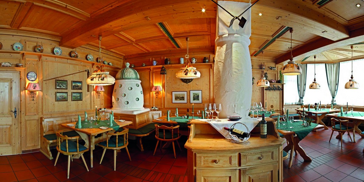 Gemütliches Restaurant im Schwarzwaldstil mit Holzmöbeln, Kachelofen und dekorativen Tellern. Tische sind gedeckt, Atmosphäre ist einladend und traditionell., © © H-Hotels.com
