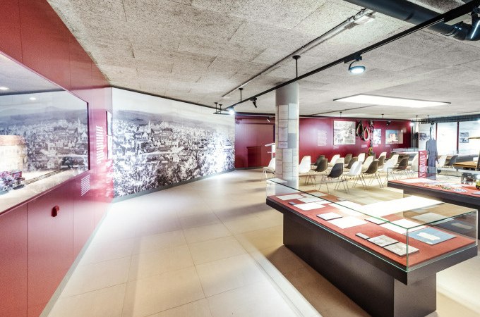 Modernes Museum mit Glasvitrinen, Sitzbereich und großem Wandbild. Helle Beleuchtung und rote Wände schaffen eine einladende Atmosphäre., © Stadt Göppingen Modernes Museum mit Glasvitrinen, Sitzbereich und großem Wandbild. Helle Beleuchtung und rote Wände schaffen eine einladende Atmosphäre., © Stadt Göppingen