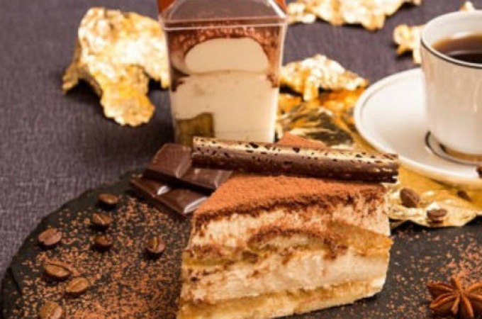 Ein Teller mit Tiramisu, Schokolade und einer Tasse Kaffee, dekoriert mit Kaffeebohnen und goldenen Blättern auf einem dunklen Tuch., © WTM GmbH Waiblingen