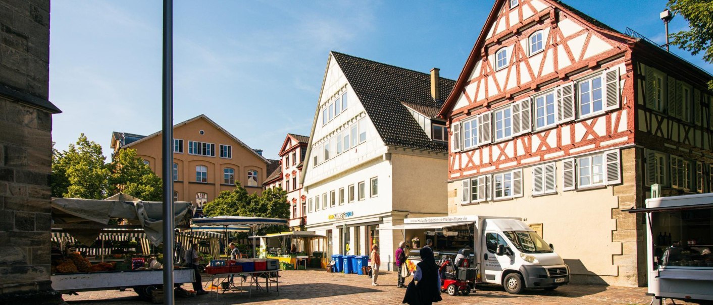 Ein sonniger Marktplatz in Schw&auml;bisch Gm&uuml;nd mit historischen Fachwerkh&auml;usern und Marktst&auml;nden. Menschen schlendern durch die Altstadt., &copy; Stuttgart-Marketing GmbH, Sarah Schmid