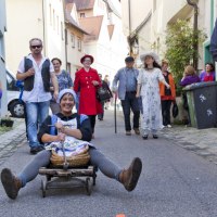 Frau auf kleinem Wagen in schmaler Gasse, umgeben von fr&ouml;hlichen Menschen. Historische Kleidung und entspannte Atmosph&auml;re., &copy; Stadt Besigheim