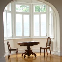 Ein heller Raum mit Erkerfenster, rundem Tisch und St&uuml;hlen. An der Wand h&auml;ngen Fotos und Texte, daneben Vitrinen mit B&uuml;chern., &copy; Gemeindearchiv Bad Boll