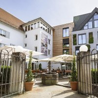 Hotel-Restaurant Schwanen mit moderner Fassade, Terrasse mit Sonnenschirmen und dekorativen Pflanzen. Historisches Tor im Vordergrund., © Hotel-Restaurant Schwanen
