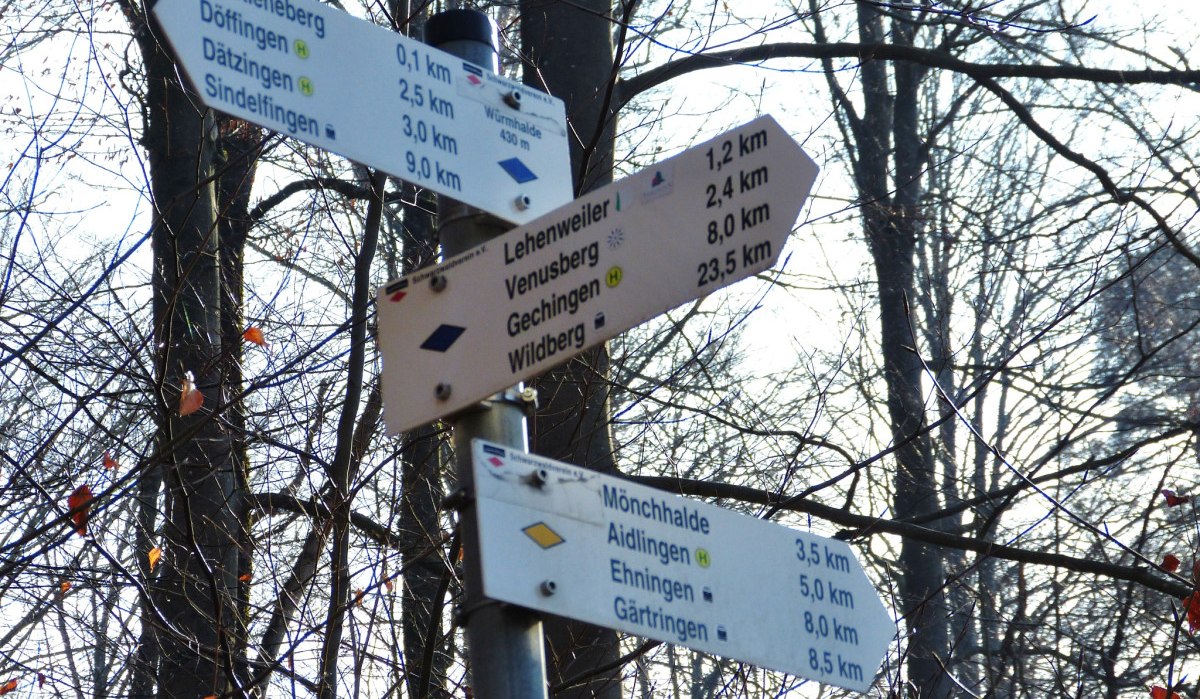 Wegweiser im Wald zeigt Entfernungen zu Orten wie Lehenweiler, Venusberg und Wildberg. Herbstliche Bäume im Hintergrund., © Natur.Nah. Schönbuch & Heckengäu
