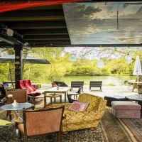 Gemütliche Sitzecke mit bunten Möbeln und Teppichen am Beutwangsee. Blick auf das Wasser und grüne Bäume im Hintergrund., © SMG, Sarah Schmid