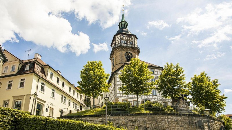 Der Backnanger Stadtturm ragt über Fachwerkhäuser und Bäume unter blauem Himmel., © SMG, Sarah Schmid Der Backnanger Stadtturm ragt über Fachwerkhäuser und Bäume unter blauem Himmel., © SMG, Sarah Schmid