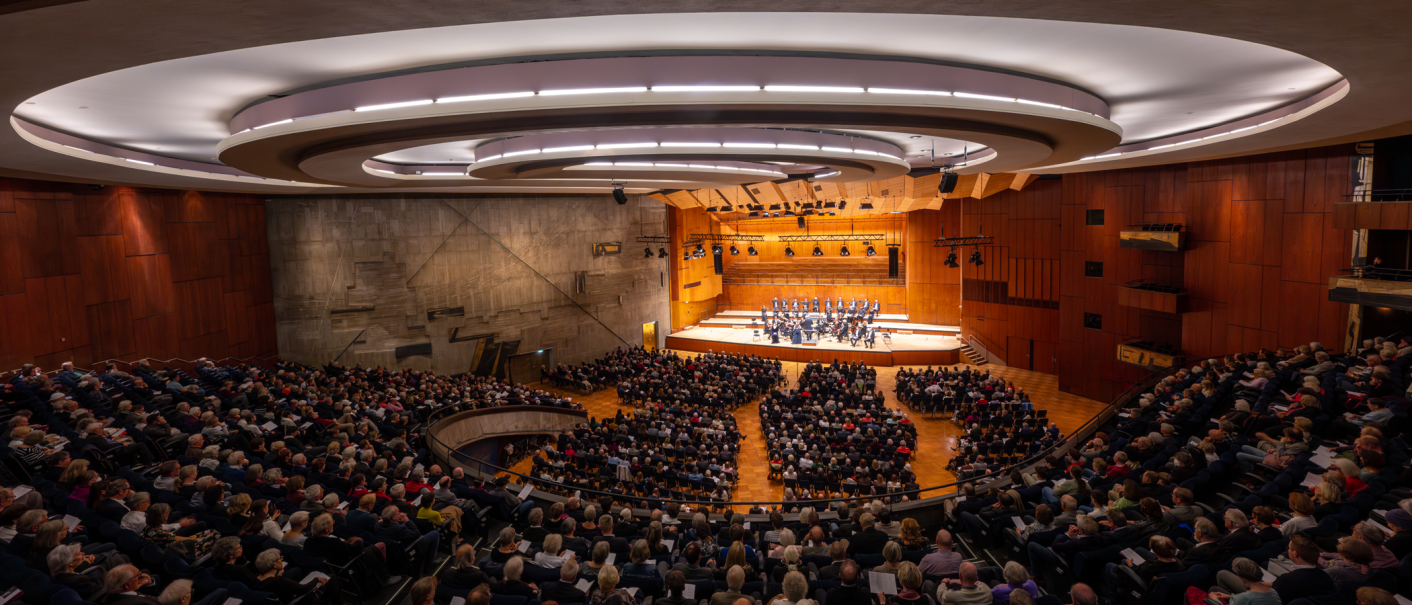 Ein gro&szlig;er Konzertsaal mit modernem Design, gef&uuml;llt mit Zuschauern. Auf der B&uuml;hne spielt ein Orchester. Die Architektur ist beeindruckend., &copy; Holger Schneider