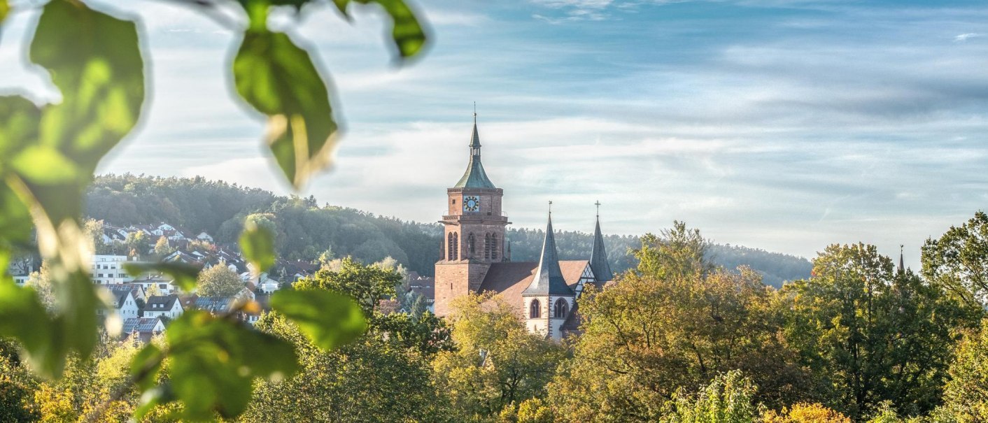 Die Peter und Paul Kirche in Weil der Stadt erhebt sich majest&auml;tisch &uuml;ber die herbstliche Landschaft, umgeben von buntem Laub und klarem Himmel., &copy; &copy; Stuttgart-Marketing GmbH, Martina Denker