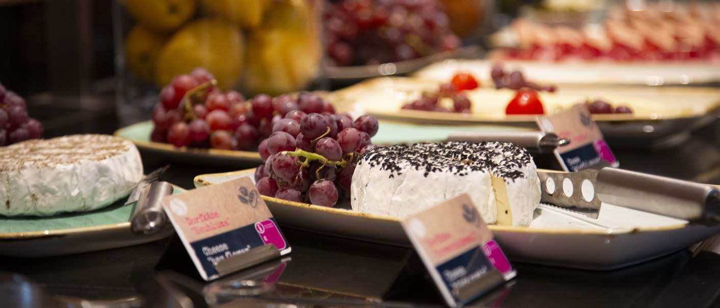 Frühstücksbuffet mit Käse und Trauben auf Tellern. Im Vordergrund ein Käsemesser und Beschriftungen., © MASEVEN Stuttgart SI-Centrum Frühstücksbuffet mit Käse und Trauben auf Tellern. Im Vordergrund ein Käsemesser und Beschriftungen., © MASEVEN Stuttgart SI-Centrum