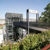 Moderne Jugendherberge in Stuttgart mit Glasfassade und Brücke, umgeben von grüner Vegetation und Stadtblick im Hintergrund., © TOMAS