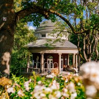 Ein rundes Teehaus mit S&auml;ulen im Wei&szlig;enburgpark, umgeben von gr&uuml;nen B&auml;umen und bl&uuml;henden Blumen im Vordergrund., &copy; Thomas Niederm&uuml;ller