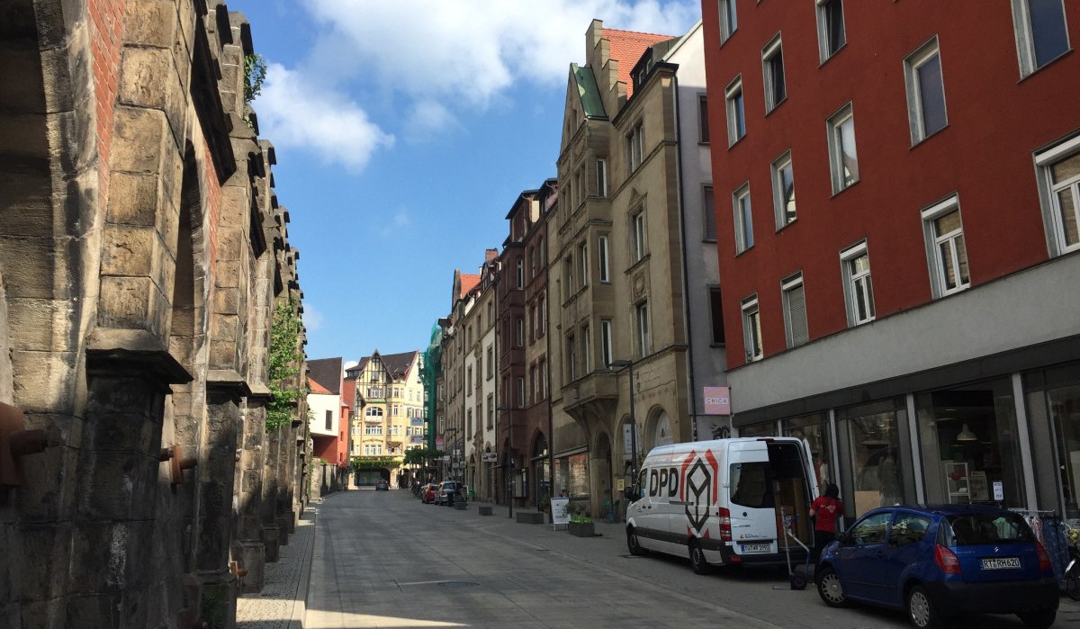 Straße in Tübingen mit historischen Gebäuden, einem Lieferwagen und einem Auto. Links sind alte Steinmauern, rechts moderne Fassaden. Blauer Himmel., © www.pro-cycl.de Straße in Tübingen mit historischen Gebäuden, einem Lieferwagen und einem Auto. Links sind alte Steinmauern, rechts moderne Fassaden. Blauer Himmel., © www.pro-cycl.de