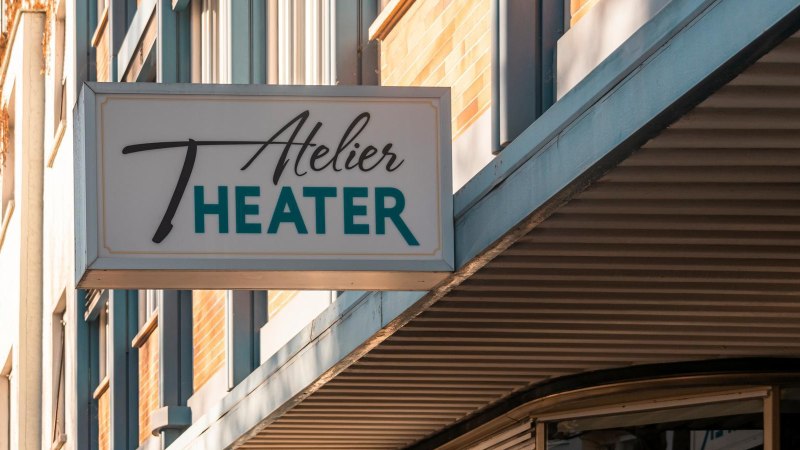 Ein Schild mit der Aufschrift 'Atelier Theater' hängt an einem Gebäude. Die Fassade ist modern und das Wetter ist sonnig., © SMG, Sarah Schmid Ein Schild mit der Aufschrift 'Atelier Theater' hängt an einem Gebäude. Die Fassade ist modern und das Wetter ist sonnig., © SMG, Sarah Schmid