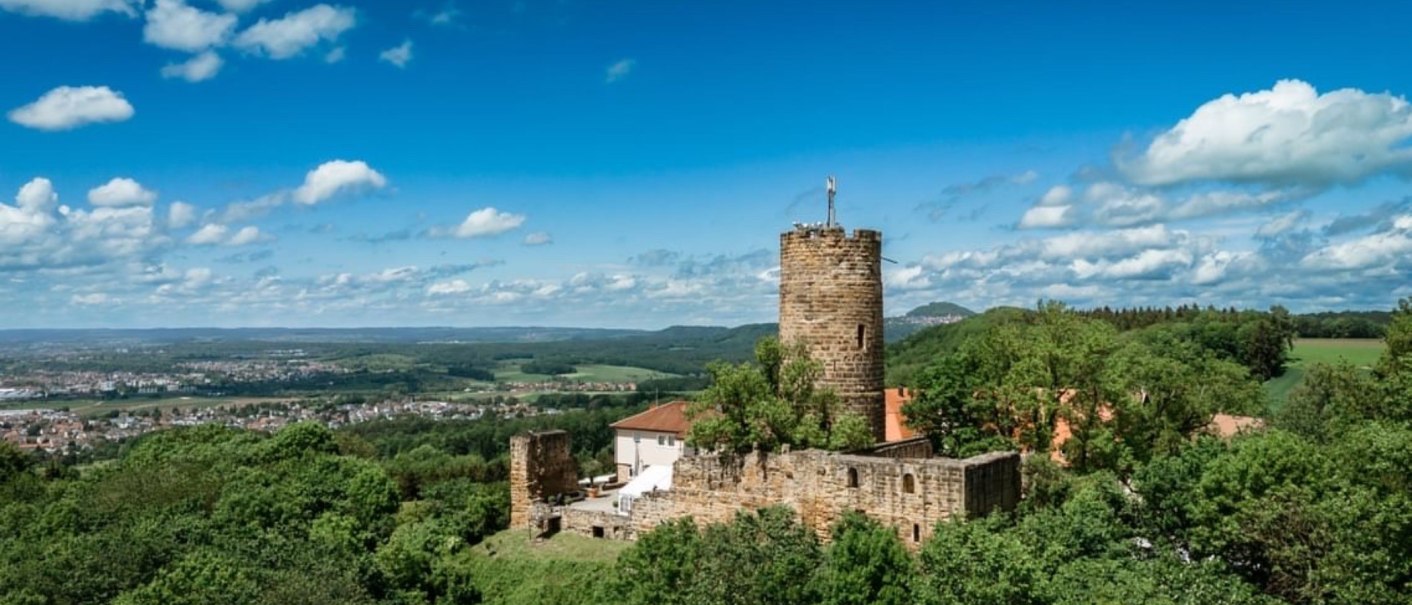 Burg Staufeneck thront auf einem bewaldeten Hügel, umgeben von grüner Landschaft und unter einem blauen Himmel mit weißen Wolken., © Christian Prerauer Burg Staufeneck thront auf einem bewaldeten Hügel, umgeben von grüner Landschaft und unter einem blauen Himmel mit weißen Wolken., © Christian Prerauer