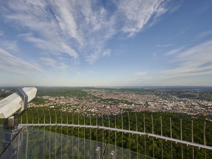 Panoramablick vom Fernsehturm Stuttgart auf die Stadt und gr&uuml;ne W&auml;lder, mit einem Fernglas im Vordergrund und blauem Himmel., &copy; SWR Media Services GmbH / Fernsehturm Stuttgart
