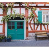 Fachwerkhaus mit grüner Tür und Fensterläden, Weinreben ranken an der Fassade. Eine Bank steht davor, umgeben von Blumentöpfen., © Eigenbetrieb Tourismus und Citymanagement Schorndorf