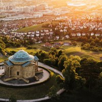 Luftaufnahme der Grabkapelle auf dem Württemberg in Stuttgart, umgeben von Weinbergen und Stadtlandschaft im Sonnenuntergang., © SMG, Cornelius Bierer Luftaufnahme der Grabkapelle auf dem Württemberg in Stuttgart, umgeben von Weinbergen und Stadtlandschaft im Sonnenuntergang., © SMG, Cornelius Bierer
