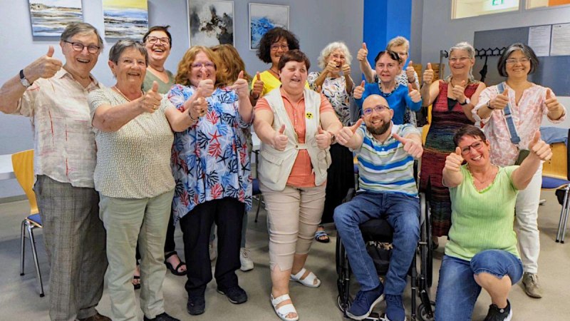 Eine Gruppe von Menschen in einem Raum, die fröhlich Daumen hoch zeigen. Sie stehen und sitzen zusammen, lächelnd, vor einer Wand mit Bildern., © Bürgerengagement und Bürgerhäuser Eine Gruppe von Menschen in einem Raum, die fröhlich Daumen hoch zeigen. Sie stehen und sitzen zusammen, lächelnd, vor einer Wand mit Bildern., © Bürgerengagement und Bürgerhäuser