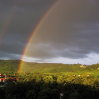 Doppelter Regenbogen über grüner Landschaft mit Häusern, dunklen Wolken und Sonnenlicht auf den Hügeln., © Stuttgart-Marketing GmbH Doppelter Regenbogen über grüner Landschaft mit Häusern, dunklen Wolken und Sonnenlicht auf den Hügeln., © Stuttgart-Marketing GmbH