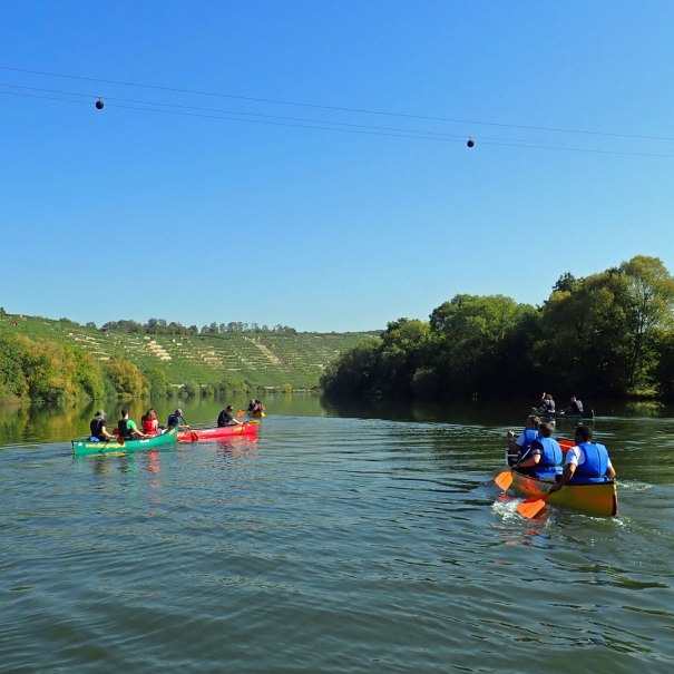 Kanufahrer genießen eine Fahrt auf dem Neckar, umgeben von grünen Weinbergen und klarem Himmel., © Die Zugvögel - Kanu-Tours und mehr Kanufahrer genießen eine Fahrt auf dem Neckar, umgeben von grünen Weinbergen und klarem Himmel., © Die Zugvögel - Kanu-Tours und mehr