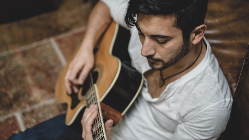Ein Mann in einem wei&szlig;en Hemd spielt konzentriert auf einer Akustikgitarre. Die Szene wirkt entspannt und k&uuml;nstlerisch., &copy; Kulturstiftung Hohenlohe