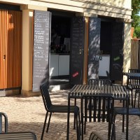 Außenbereich des 1819 Bistros am Wirtemberg mit schwarzen Tischen und Stühlen auf gepflastertem Boden, umgeben von grüner Vegetation., © 1819 Bistro am Wirtemberg