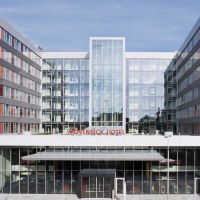 Das Mövenpick Hotel Stuttgart Airport zeigt eine moderne Glasfassade mit abgerundeten Ecken und roten Akzenten., © Mövenpick Hotel Stuttgart Airport