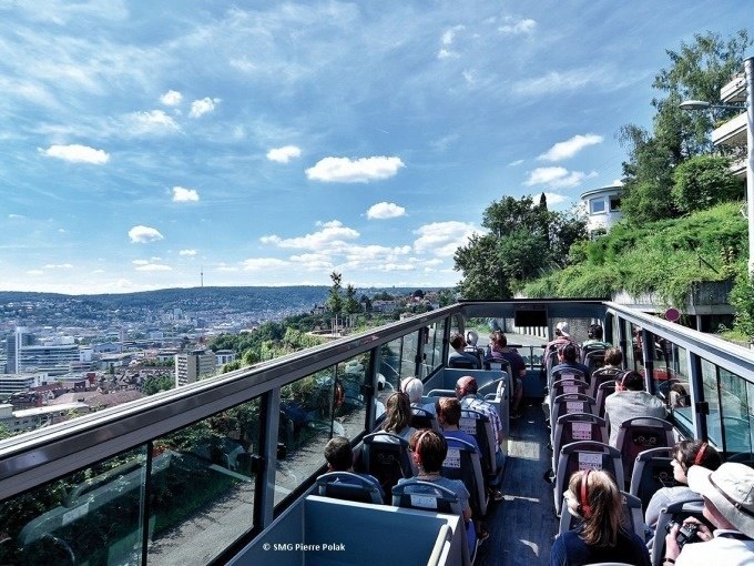 Touristen sitzen in einem offenen Doppeldeckerbus und genie&szlig;en den Blick auf die Stadt Stuttgart unter einem blauen Himmel mit Wolken., &copy; SMG, Pierre Polak