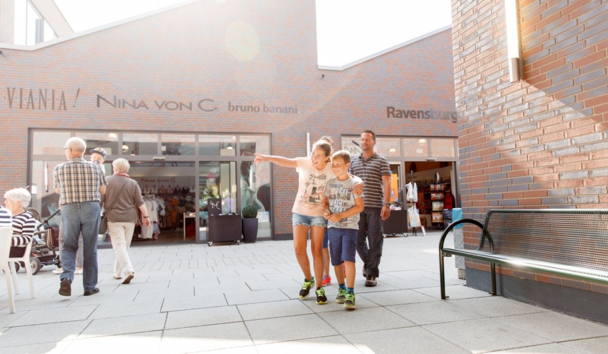 Familie spaziert fröhlich im City Outlet Geislingen. Im Hintergrund sind Geschäfte und weitere Besucher zu sehen., © Landkreis Göppingen