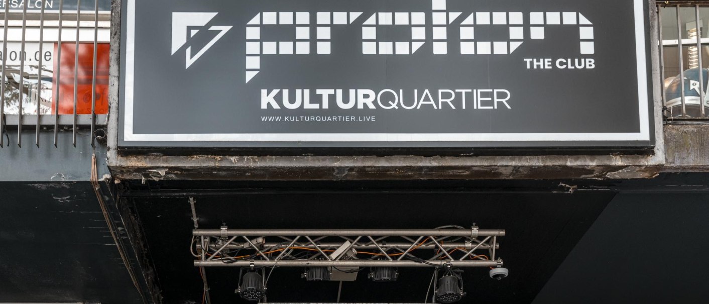 Schild von Proton The Club im Kulturquartier mit Website-Adresse. Darunter Beleuchtung und Metallstruktur sichtbar., © Stuttgart Marketing GmbH, Sarah Schmid Schild von Proton The Club im Kulturquartier mit Website-Adresse. Darunter Beleuchtung und Metallstruktur sichtbar., © Stuttgart Marketing GmbH, Sarah Schmid