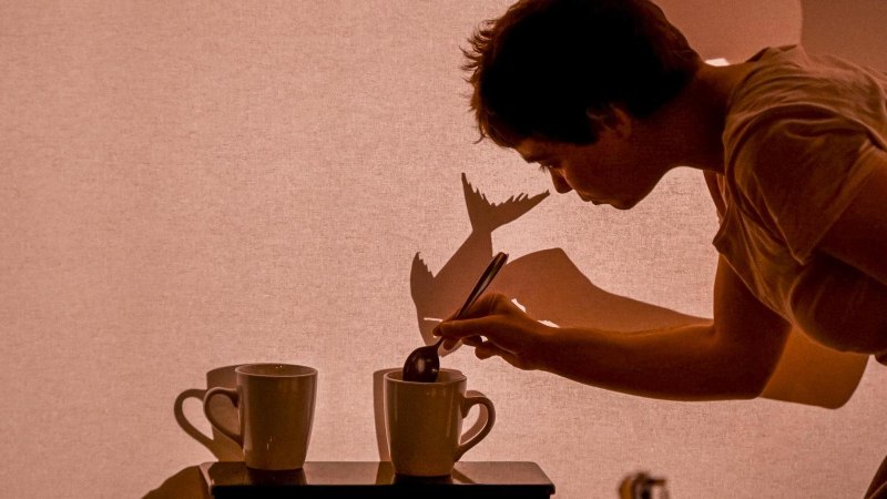 Person r&uuml;hrt in einer Tasse, projiziert Schatten auf Leinwand. Kreatives Spiel mit Licht und Schatten., &copy; FITZ! Stuttgart