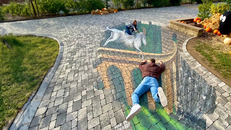 Zwei Personen posieren auf einer 3D-Stra&szlig;enmalerei, die eine Br&uuml;cke und ein Einhorn zeigt. Die Illusion wirkt realistisch auf dem gepflasterten Boden., &copy; Erlebnispark Tripsdrill